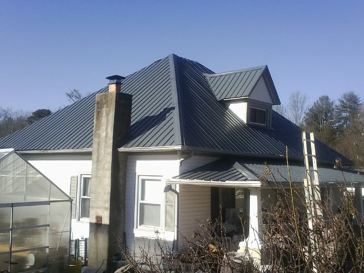 Dark blue standing seam metal roof on a white farmhouse with dormer — Slate & Tile Roof Repair by Roofing Brothers in South Amboy