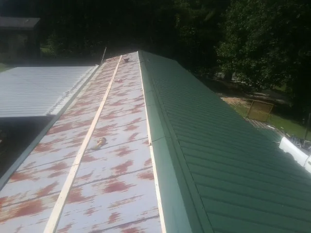 Old rusted panels beside newly installed green metal roofing — Wind Damage Roof Repair by Roofing Brothers in South Amboy
