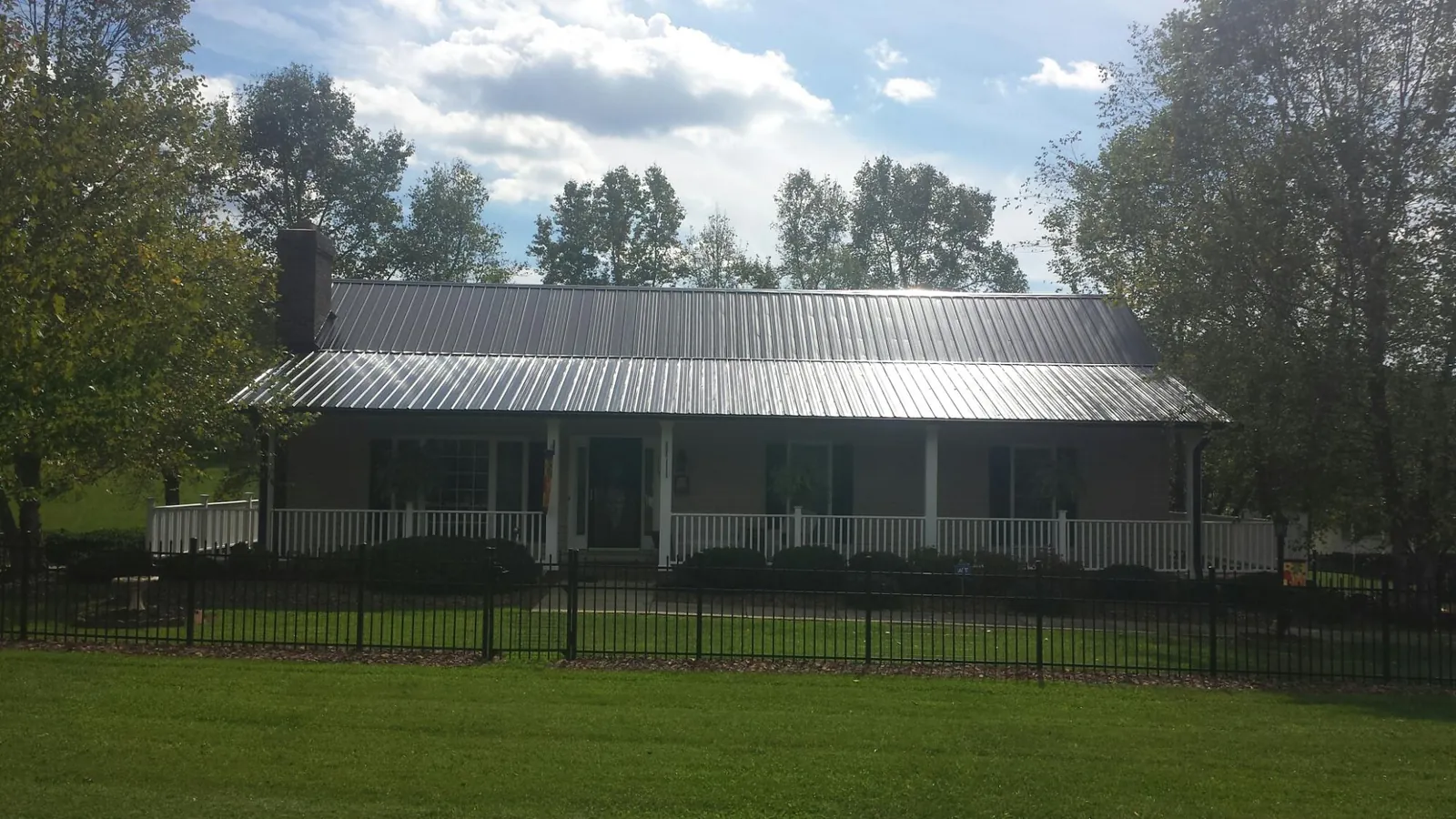 Gray metal roof on a brick ranch with a full width front porch — Gutter Guard Installation work by our crew in South Amboy