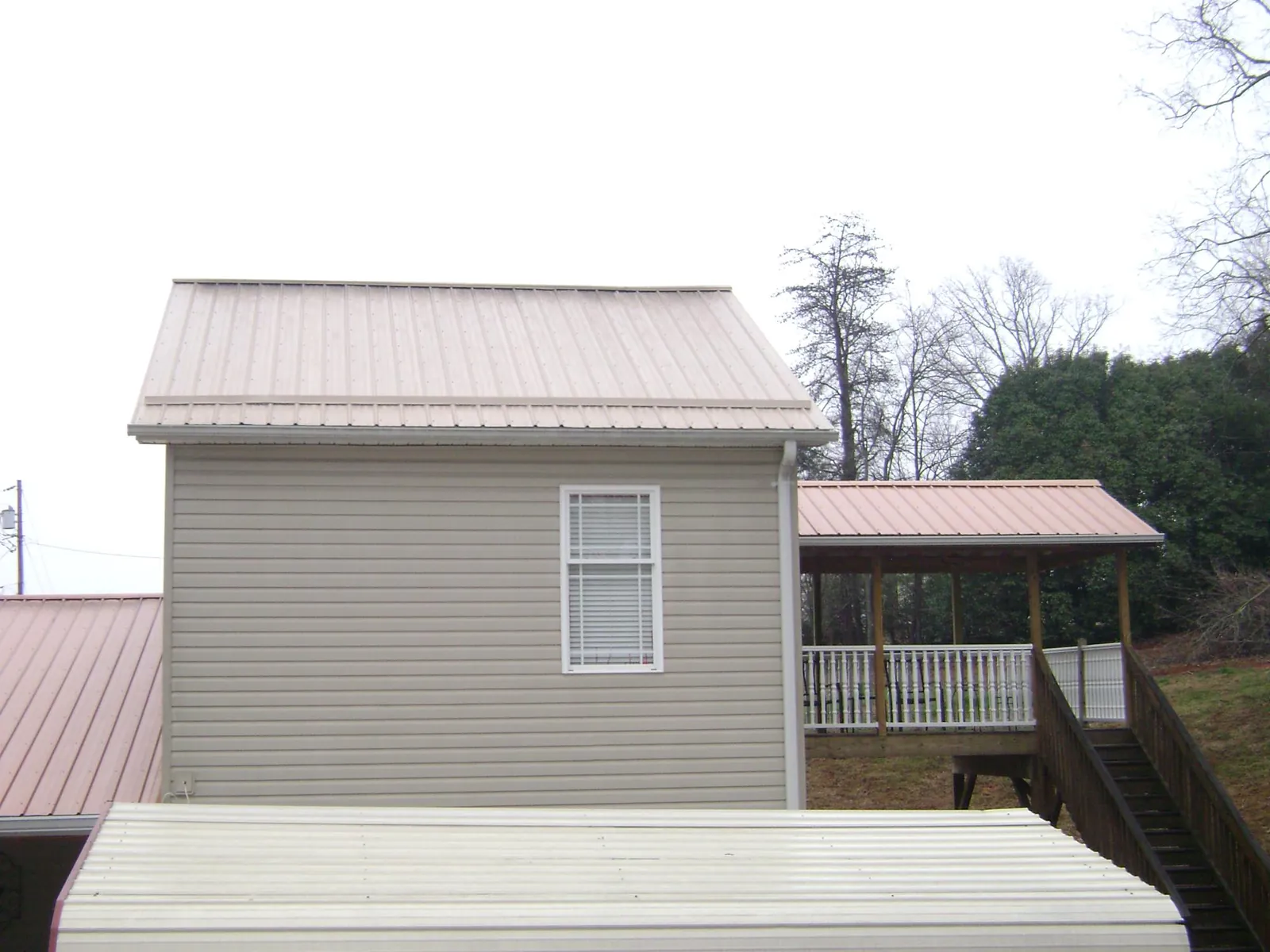Tan metal roofs on a two story addition and attached porch, from a Roof Replacement job in South Amboy